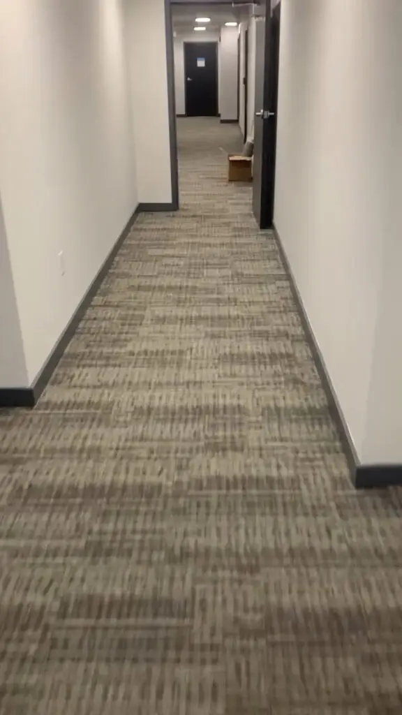 Long hotel or apartment corridor with neutral-toned commercial grade carpet tiles.