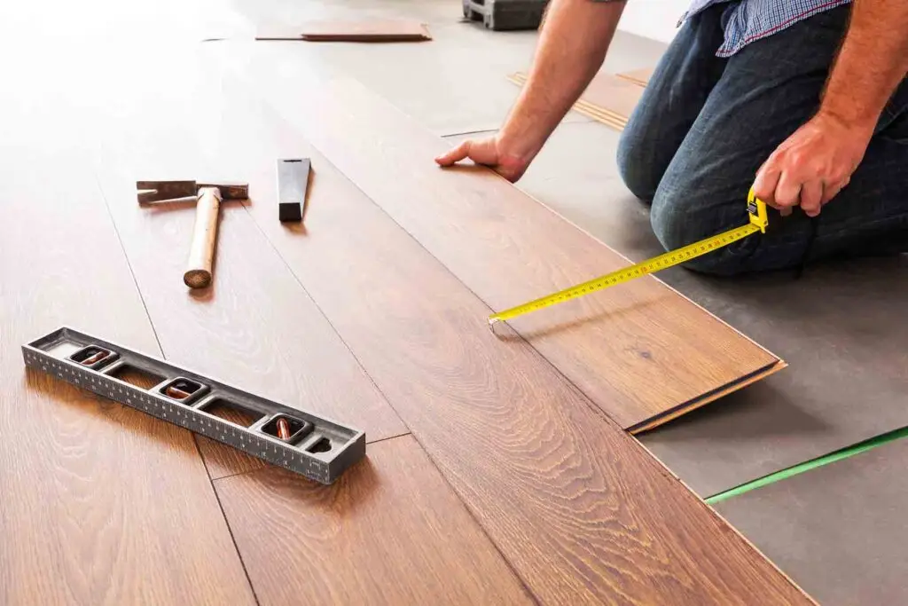 A professional measures a laminate flooring plank during installation, demonstrating precision in creating a durable and attractive floor.